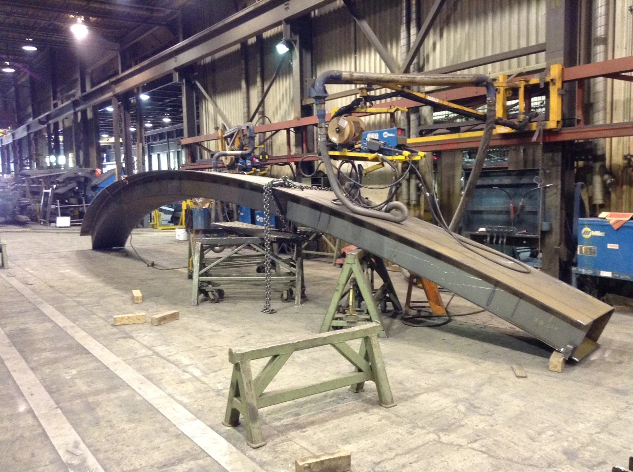 Curved structural member supported in a fabrication workshop